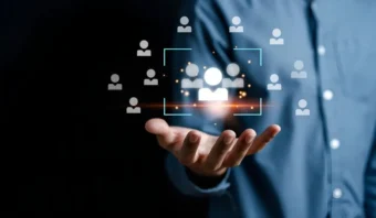 Una persona extiende su mano con íconos digitales de personas y un cuadrado brillante, que simboliza el lado humano del CRM y el proceso de selección o selección de individuos, sobre un fondo oscuro.