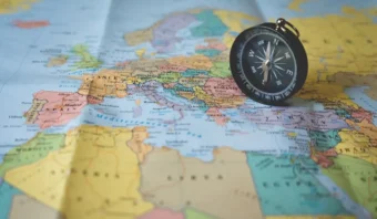 Una brújula negra reposa sobre un mapa detallado de Europa, en el que también son visibles países de África y Oriente Medio.