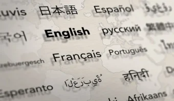 La palabra "inglés" aparece en negrita entre los nombres de otros idiomas como francés, español y ruso sobre un fondo de mapa mundial borroso, evocando la esencia multicultural de un auténtico Mundo de Babel.