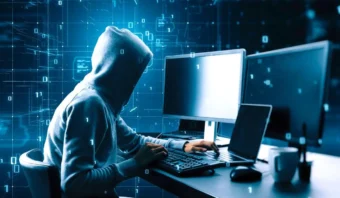 Una persona con una sudadera con capucha se sienta en un escritorio con varios monitores, escribiendo en un teclado, con gráficos de código binario digital en el fondo, concentrado en estrategias para evitar el hackeo.