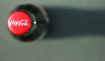 Una botella de Coca-Cola vista desde arriba, que muestra la tapa roja con el logotipo, resalta por qué Coca-Cola sale del Top Ten, con una sombra proyectada a la derecha.