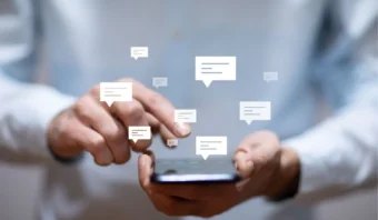 Una persona que usa un teléfono inteligente, con burbujas de mensajes ilustradas sobre la pantalla para representar la actividad de mensajes de texto o mensajería, resaltando la empatía textual y el sexting en las conversaciones digitales.