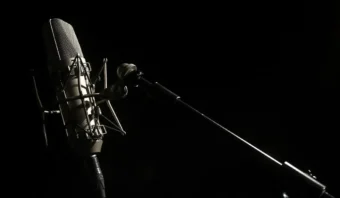 Un micrófono de estudio profesional sobre un soporte está iluminado contra un fondo negro oscuro, como si estuviera preparado para capturar cada palabra, incluso un error discursivo del Presidente.