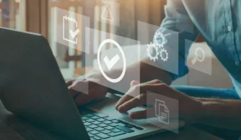 Persona escribiendo en una computadora portátil con íconos flotantes transparentes (marcas de verificación, engranajes, una lupa y un documento) que representan el flujo de trabajo digital o la gestión de tareas guiada por las reglas para una organización eficiente.