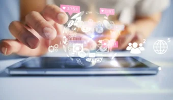 Una mano interactúa con una tableta mientras los íconos de comunicación y redes sociales digitales flotan sobre la pantalla, simbolizando la conectividad en línea, la tecnología y los consejos para los primeros pasos en la comunicación en línea.