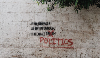 Un grafiti en una pared de piedra blanca dice: "Si repites una mentira con suficiente frecuencia, se convierte en verdad", con la palabra "verdad" tachada y reemplazada por "política" en pintura en aerosol roja: una aguda interpretación de la distracción mediática.