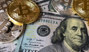 Un grupo de monedas encima de un billete de cien dólares que muestra la brecha de género.