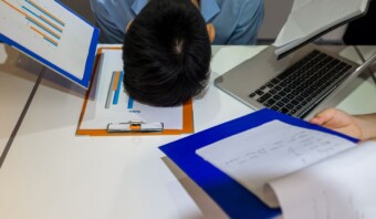 Un grupo de personas sentadas en un escritorio con papeles en la cabeza.