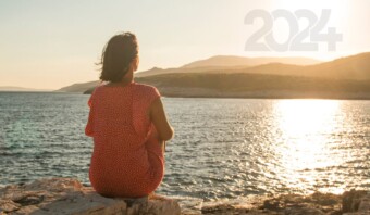 Una mujer talentosa está sentada sobre una roca con vistas al océano.