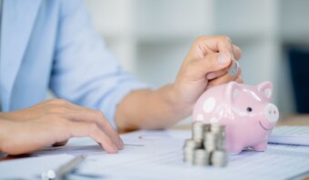 Una mujer ahorra dinero poniendo una moneda en una alcancía.
