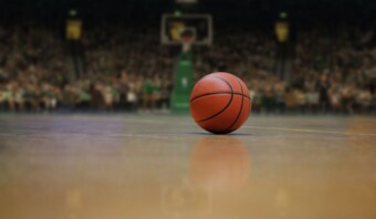 Una pelota de baloncesto se coloca en la cancha de la NBA frente a una multitud durante la temporada.