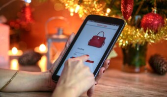 Una mano sosteniendo una tableta durante la temporada navideña.