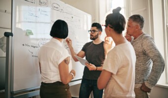 Un grupo de personas paradas alrededor de una pizarra.