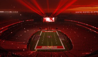 Una imagen de un estadio de fútbol iluminado por luces rojas por la noche.