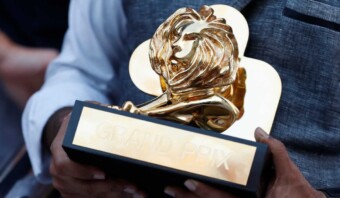 Una persona que sostiene triunfalmente un trofeo dorado con la palabra león, mostrando su victoria en un esfuerzo competitivo.