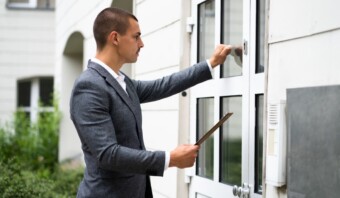 Un hombre de traje sostiene un palo frente a una cobranza extrajudicial.