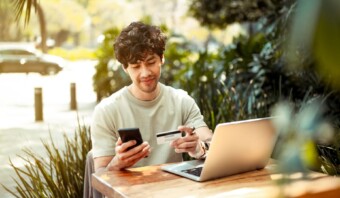 Un consumidor sentado en una mesa con una computadora portÃ¡til y una tarjeta de crÃ©dito.