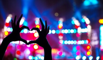 Una persona creando una forma de corazón con sus manos en un concierto, mostrando el poder del marketing experiencial.