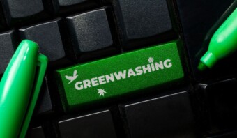 Un teclado de computadora con una tecla verde con la etiqueta "greenwashing" flanqueada por dos marcadores verdes.