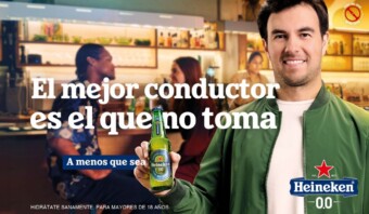 Hombre sonriente sosteniendo una botella de Heineken 0.0 con un mensaje que promueve la conducciÃ³n responsable y la cerveza sin alcohol, junto a