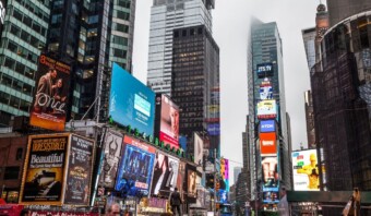 Una animada escena urbana en Times Square con numerosos carteles iluminados y algunos anuncios malos esparcidos entre los anuncios de los edificios altos.