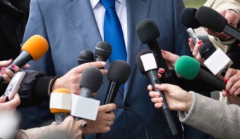 Numerosos micrófonos en manos de periodistas apuntaron hacia una persona de traje azul, captando su declaración en municipios y comunicación política.