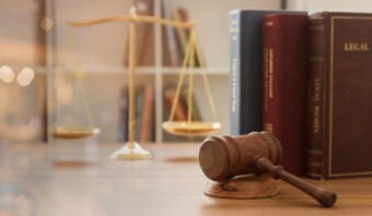 Un mazo descansa sobre un escritorio de madera frente a libros jurÃ­dicos y una balanza, que simboliza la justicia y el derecho, componentes integrales de los procesos legislativos.