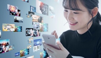 Una persona sonríe mientras mira un teléfono inteligente. Imágenes digitales flotan y representan diversas escenas que incluyen tecnología, paisajes y personas.