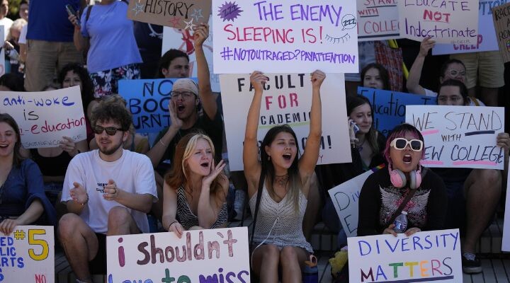 Un grupo de estudiantes se sientan y se paran sosteniendo carteles de protesta con mensajes sobre educación, diversidad y oposición a políticas anti-woke, denunciando noticias falsas que socavan sus voces.