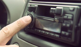 La mano de una persona ajusta la perilla del volumen de la radio del automóvil.