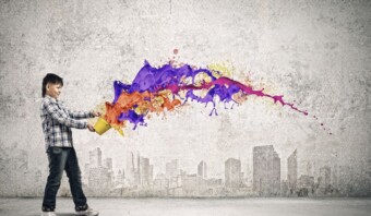 Un niño vierte pintura colorida de un balde sobre un fondo gris con contornos de paisajes urbanos, encarnando un vibrante concepto creativo.