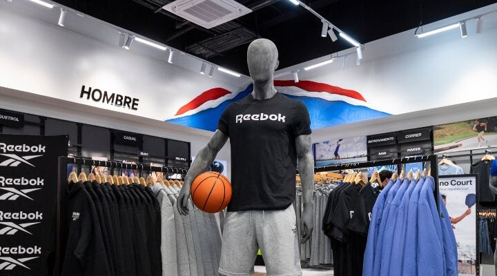 Un maniquÃ­ con camiseta y pantalones cortos Reebok sostiene una pelota de baloncesto en la secciÃ³n "Hombre" de la tienda de ropa deportiva de Mundo E.