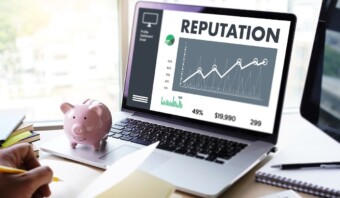 Una computadora portátil que muestra un panel de gestión de reputación de marca con un gráfico y estadísticas se encuentra junto a una alcancía rosa.