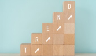 Bloques de madera dispuestos en orden ascendente con flechas apuntando hacia arriba y letras que deletrean "TREND" en ellos.