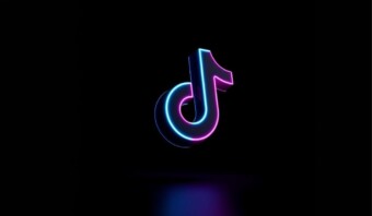 Logotipo de neón de TikTok sobre un fondo oscuro, mejorado con efectos de iluminación rosa y azul, que muestra soluciones publicitarias en TikTok.