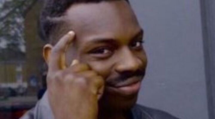 Persona sonriendo con el dedo apuntando a su sien, transmitiendo un gesto pensativo, como si estuviera reflexionando sobre la frase "qué con estos chavos".