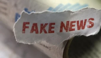 Periódico roto con las palabras "NOTICIAS FALSAS" claramente visibles en texto rojo, resaltando el problema generalizado de la desinformación.