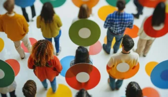 Un grupo de personas se encuentra de pie sobre puntos circulares de colores en el suelo, vistos desde arriba.