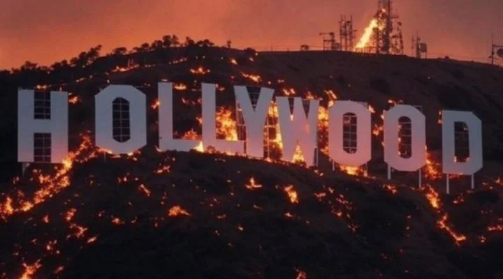 El letrero de Hollywood en la ladera de una colina está rodeado de llamas y humo de un incendio forestal al anochecer.