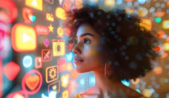 Una persona mira una interfaz digital colorida con varios íconos de aplicaciones, incluidos símbolos de redes sociales, música y cámara, que reflejan una luz de neón vibrante en su rostro.