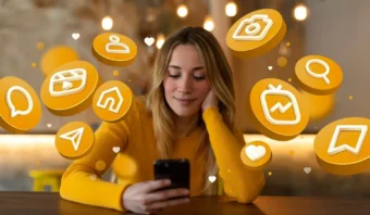 Mujer con un suéter amarillo mirando su teléfono, rodeada de íconos y símbolos flotantes de redes sociales.