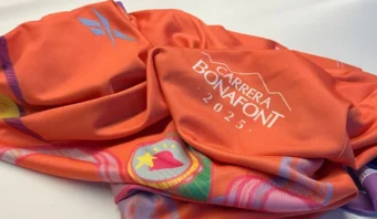 Una tela de color naranja con el estampado “Carrera Bonafont 2023”, con dibujos multicolores y un emblema visible.