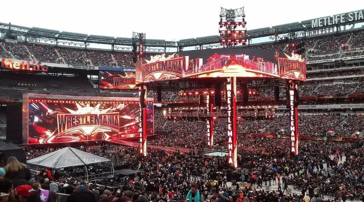 Gran multitud en el MetLife Stadium asistiendo a un evento de WrestleMania, con luces brillantes y pantallas grandes que muestran el logotipo de WrestleMania en el escenario principal.