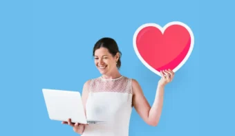 Una mujer sostiene un gran recorte en forma de corazón en una mano y una computadora portátil en la otra, de pie frente a un fondo azul simple: una imagen perfecta para campañas de marketing en redes sociales.