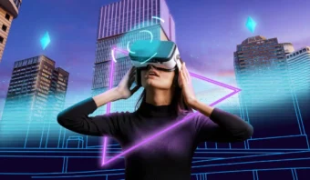 Una persona que usa un casco de realidad virtual se encuentra frente a altos edificios de la ciudad, rodeada de gráficos geométricos de neón y efectos de luz azul, capturando la esencia de la transformación digital en un paisaje urbano inmersivo.