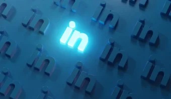 Los logotipos 3D azules de LinkedIn están dispuestos en un patrón llamativo, con un logotipo "in" central que brilla intensamente, lo que lo hace destacar sobre el fondo más oscuro.