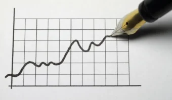 Una pluma fuente dibuja un gráfico de líneas con tendencia ascendente en una hoja de papel cuadriculado, ilustrando una curva de aprendizaje positiva y un crecimiento constante.
