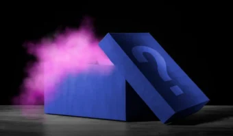 Una caja azul con un signo de interrogación tiene la tapa abierta y libera humo rosa sobre un fondo oscuro: una imagen que te inspira a pensar fuera de la caja.