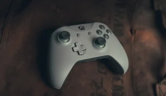 Un controlador inalámbrico Xbox gris reposa sobre una superficie marrón, invitando a momentos de gamificación y juego inmersivo.
