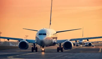 Un avión comercial de Volaris rueda por la pista al atardecer, con otro avión visible al fondo. ¡Qué escena tan impresionante!.